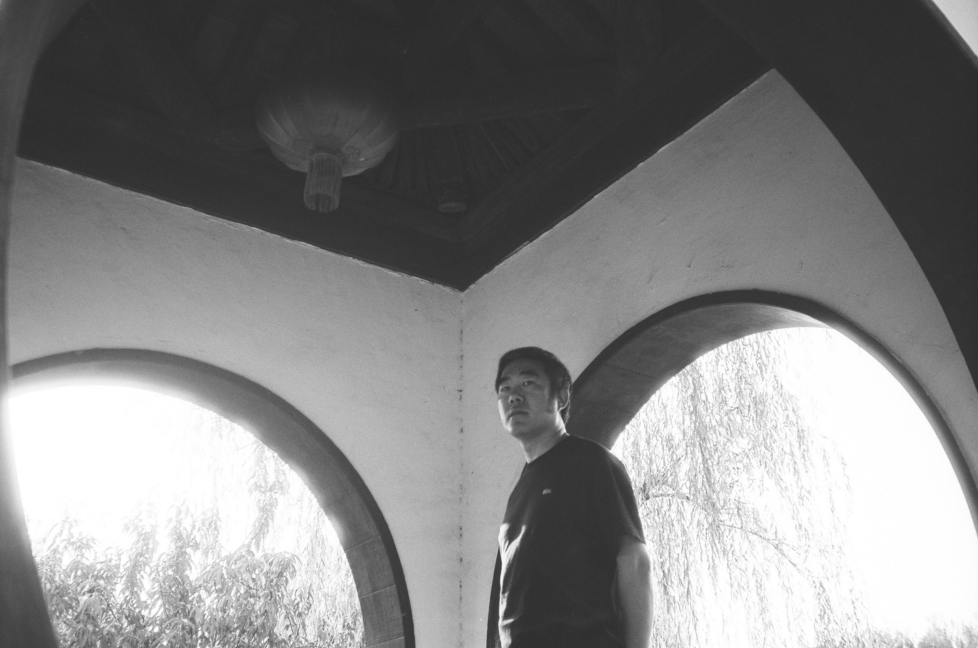 A black and white photo of Meng in a building surrounded by nature